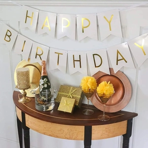 Elegant white and gold Happy Birthday bunting banner hanging over a festive party table set