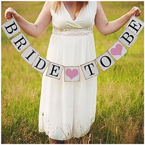 Banderole Bride To Be tenue à la main avec cœurs roses pour décoration de mariage en plein air