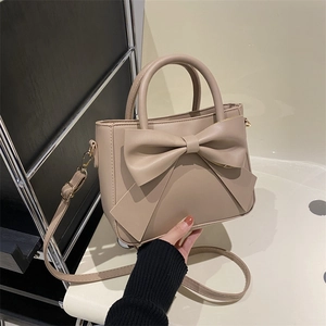 Chic beige bucket bag with large bow detail and adjustable shoulder strap for women