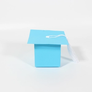 Detail view of light blue graduation cap gift box with a white tassel on white background
