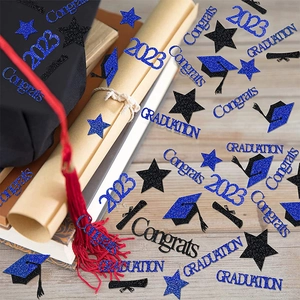 Detail of glitter 2023 graduation confetti with stars and grad caps on party table