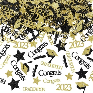 Macro detail of black and gold glitter graduation confetti with cap and star shapes