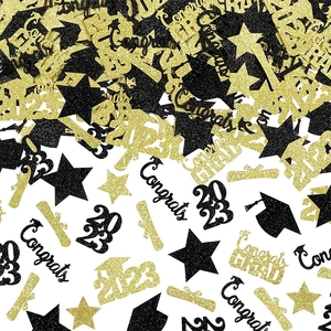 Close-up of black and gold glitter graduation confetti with stars and mini Grad caps