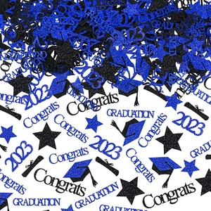 Close-up of sparkling blue and black graduation table confetti with glitter graduation caps