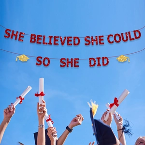 Detail of red glitter graduation banner She Believed She Could against a clear blue sky