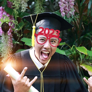 Close-up of red glitter 2023 graduation party paper glasses worn by a graduate student