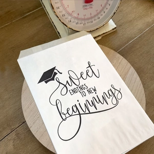 White graduation favor bags with Sweet Endings To New Beginnings print on wood tray