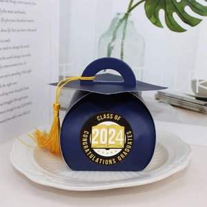 Navy blue graduation cap gift box with 2024 sticker and yellow tassel on white tray