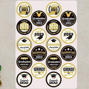 Close-up of 16 round gold and black graduation 2023 stickers with cap and scroll icons