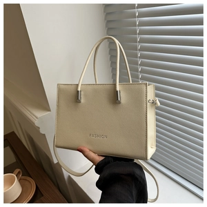 Detail der creme-rechteckigen Handtasche mit Litschitextur und geprägtem Modetext