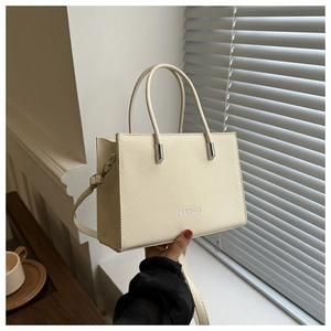 Detail der cremefarbenen Ledertasche mit FASHION-Schriftzug und Silberbeschlägen