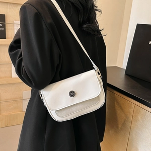 Close-up of white minimalist flap shoulder bag with round metal logo on smooth PU leather