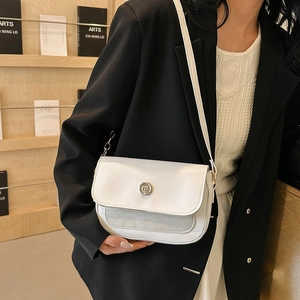 Detail of a creamy white leather shoulder bag with round silver metal lock and chain