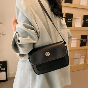 Detail of minimalist black shoulder bag with leather splicing and metal buckle