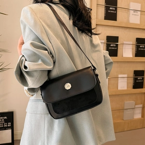 Detail of a black patchwork flap shoulder bag with a gold buckle and elegant 'm' logo