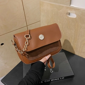 Detail of brown leather crossbody bag featuring gold logo and decorative metal chain