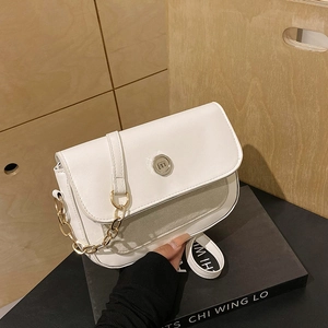 Close-up of white crossbody bag featuring mixed textures and round gold logo buckle