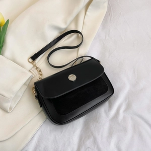 Detail of black crossbody bag featuring textured leather, suede panels and gold M buckle