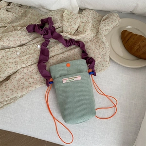 Mint green corduroy crossbody phone bag with purple pleated strap and orange drawstring