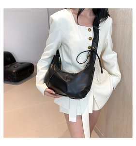 Détail d'un sac hobo en cuir mat noir avec large bandoulière et finitions dorées chic