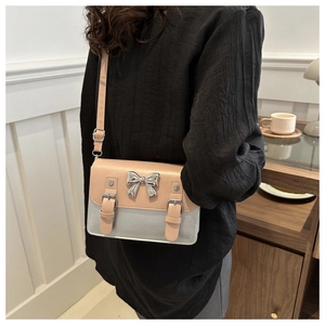Detail of a chic crossbody messenger bag with silver bow accent on a female model