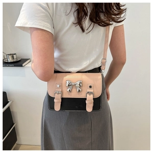 Pink and black bow satchel bag with silver metal buckle shown on a crossbody model