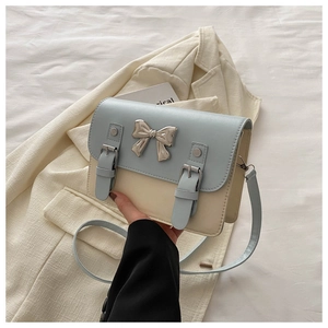 Detail of blue and beige crossbody bag with silver bow buckle and buckle straps