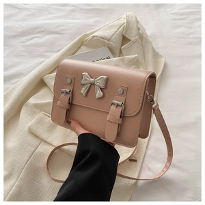 Detail of powder pink crossbody bag featuring a silver bow buckle and soft leather texture