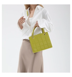 Detailed view of lime green quilted texture and gold chain on the square handbag