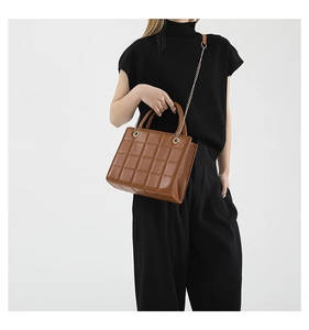 Close-up of brown quilted shoulder bag with gold chain strap and metal texture details