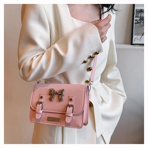 Detailed close-up of pink crossbody bag with champagne gold bow buckle and smooth leather
