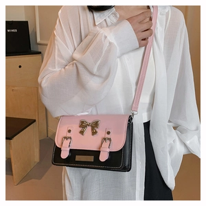 Detail of pink and black contrast crossbody bag with silver bow and buckle accents