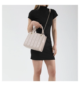 Detail of beige quilted faux leather handbag with golden chain strap and round handles