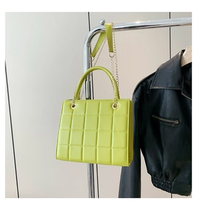 Detail of yellow-green quilted leather crossbody bag with gold chain and handle