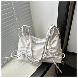 Detail of white PU leather hobo bag with drawstring pleats, bow accent and metal chain strap