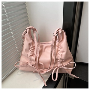 Detail of pink soft leather shoulder bag with side drawstring bow and metal chain strap
