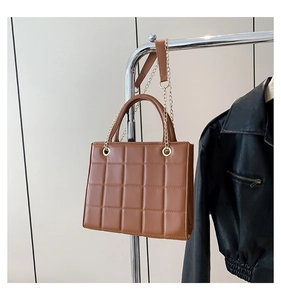 Detail of brown quilted checkerboard handbag with light gold chain and leather strap