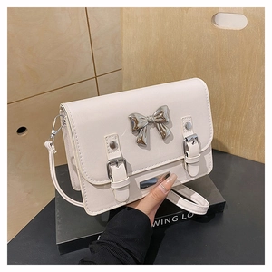 Detail of off-white crossbody bag featuring a silver metal bow and buckle accent