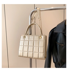 Close-up of quilted champagne gold chain bag with metallic finish on a hanger