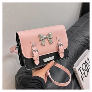 Detail of pink and black crossbody bag with silver bow ornament and white stitching