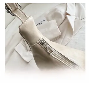 Close-up of the smooth metal zipper and reinforced strap stitching on the beige tote bag