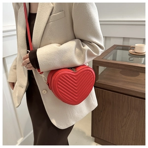 Detail of red heart-shaped chevron quilted crossbody bag with metal zipper