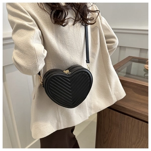 Detail of black heart-shaped crossbody bag with V-quilted pattern and gold hardware