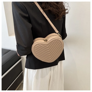 Close-up of heart-shaped beige crossbody bag with V-quilted texture and gold hardware