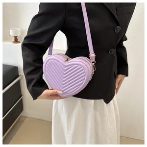 Detail of light purple heart-shaped crossbody bag with V-chevron quilting and gold hardware