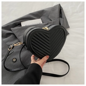 Detail of black heart-shaped crossbody bag with quilted texture and gold zipper