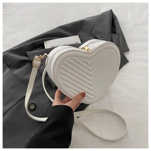 Detail of white heart-shaped crossbody bag with V-quilted faux leather and gold hardware