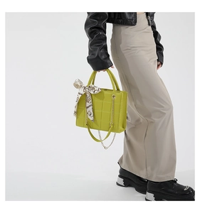 Detail einer lindgrünen Stepphandtasche mit floralem Seidentuch und goldener Kette