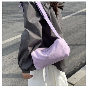 Close-up of light purple corduroy barrel bag with wide woven strap in outdoor sunlight