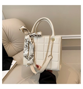 Detail der cremefarbenen Stepptasche mit gebundenem Seidentuch und goldener Kette